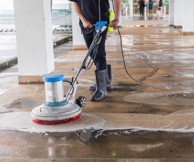 Asian worker cleaning sand wash exterior walkway using polishing machine and chemical or acid